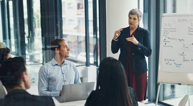 Older woman giving presentation at work - Age Discrimination